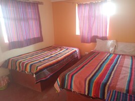 Una habitación con dos camas, cada una con una colcha a rayas de colores.