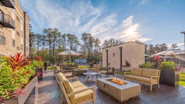 An outdoor patio with seating, a fire pit, and potted plants. - WaterWalk Extended Stay Huntsville (HUNTSVILLE)