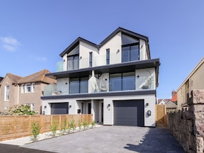 A modern two-story house with a garage, a balcony, and a well-maintained garden.