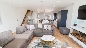 Ein modernes Wohnzimmer mit einer Eckcouch, einem runden Couchtisch und einem Kamin.