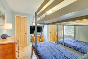 Een slaapkamer met stapelbed, bureau, lamp en raam.