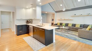 A modern kitchen with a central island, built-in appliances, and a dining area with a sofa and coffee table. - Blue Ridge Mountain Retreat: Deck & Sunroom! (Fletcher)