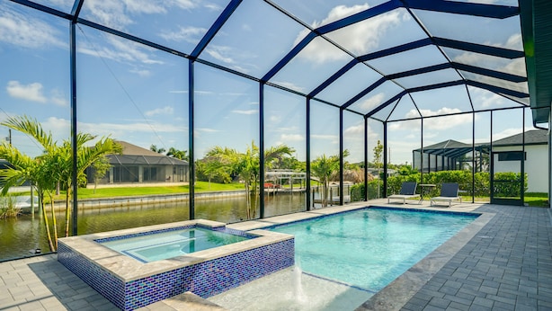 Ein Schwimmbad mit Glasveranda, eine Whirlpoolanlage und eine Terrassenfläche mit Sitzgelegenheiten.