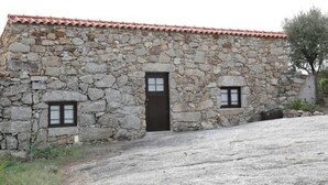 A stone building with a tiled roof, a central door, and two small windows.