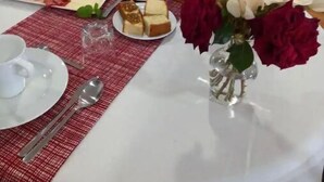 A breakfast table set with plates of food, a pitcher of juice, and a vase of flowers.
