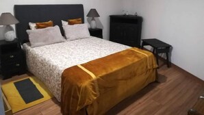 A bedroom with a bed, nightstands, a dresser, and a small table.