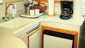 A compact kitchenette with a sink, a coffee maker, and a small refrigerator.