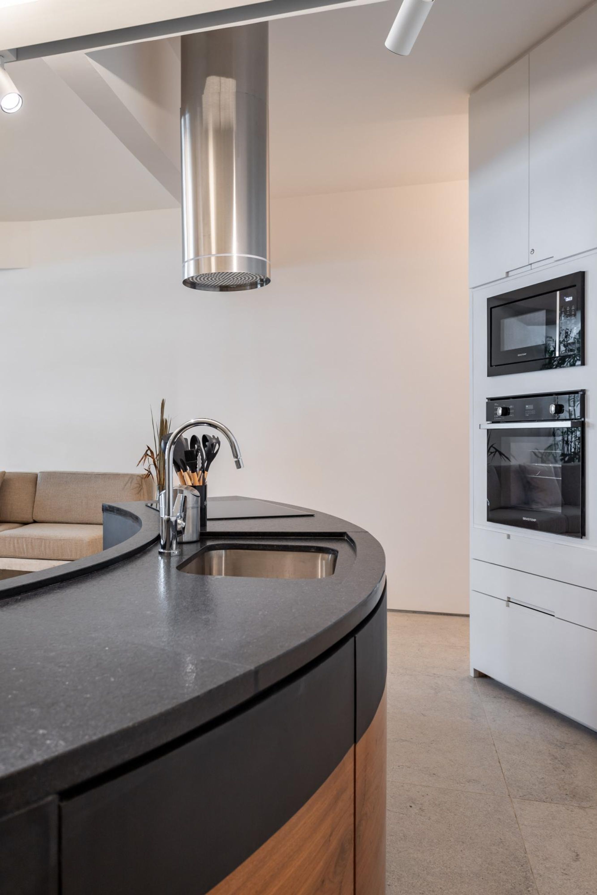 A modern kitchen with a curved island, stainless steel appliances, and a minimalist design.
