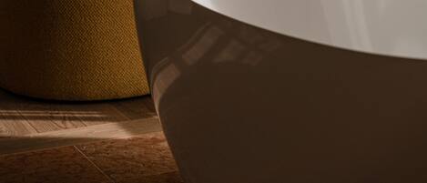 A modern room with a curved white table, a mustard-colored armchair, and beige curtains.