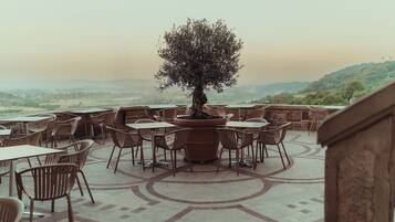 An outdoor seating area with tables and chairs arranged around a central tree.