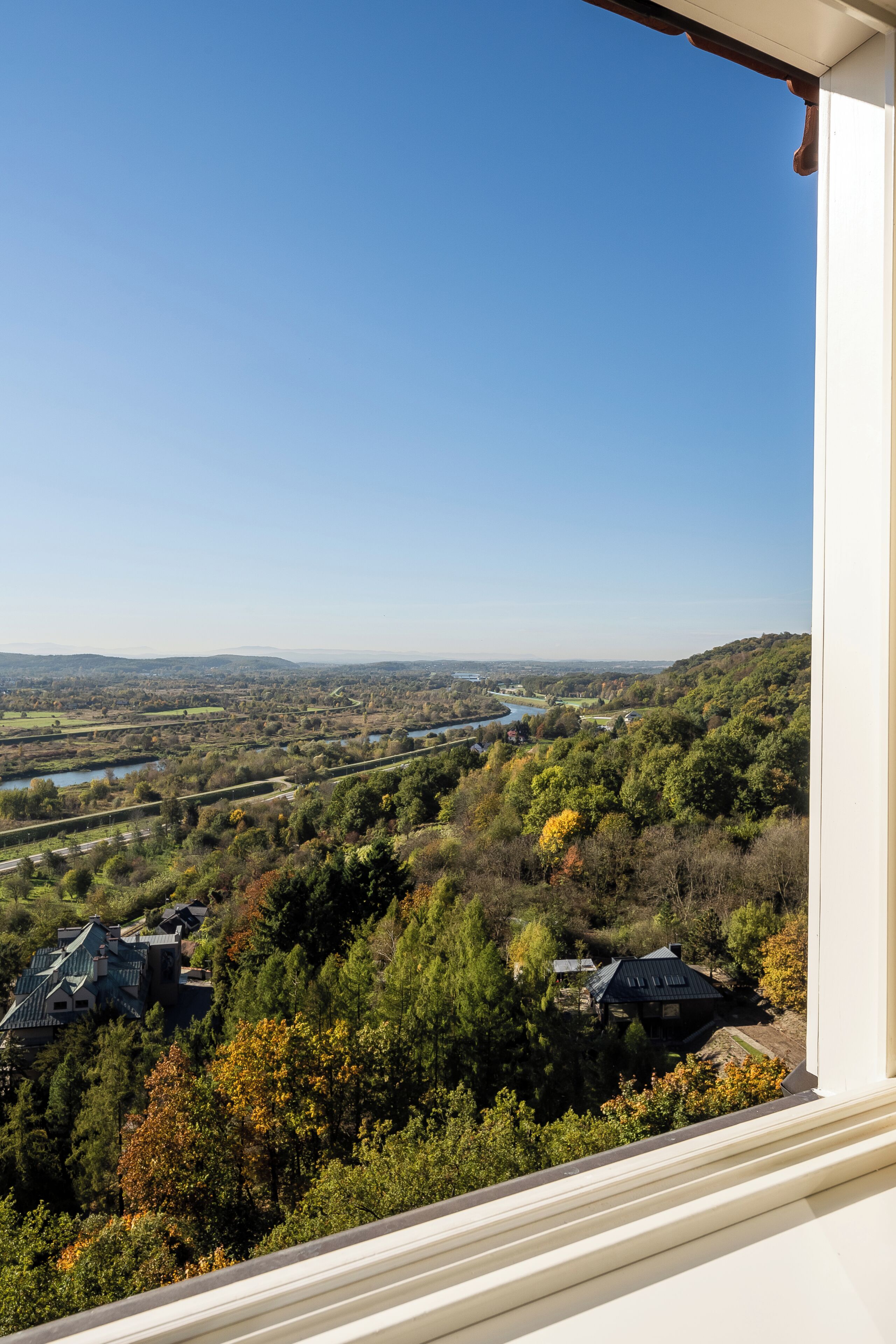 A view from a window overlooking a landscape with houses, trees, and a river.