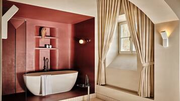A modern bathroom with a freestanding bathtub, a glass-enclosed shower, and a vanity with shelves.