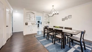 A dining area with a long table, six chairs, and a blue and white striped rug. - Game-Day Getaway NEW Stadium View Walk to ATT or Rangers (Arlington)