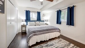 A bedroom with a bed, nightstands, a ceiling fan, and two windows with curtains. - Game-Day Getaway NEW Stadium View Walk to ATT or Rangers (Arlington)