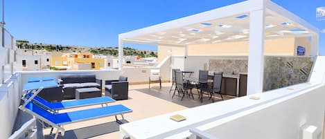 Una terraza en la azotea con mobiliario exterior, una mesa de billar y un área de comedor.