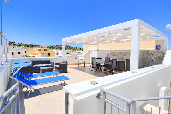 Una terraza en la azotea con mobiliario exterior, una mesa de billar y un área de comedor.
