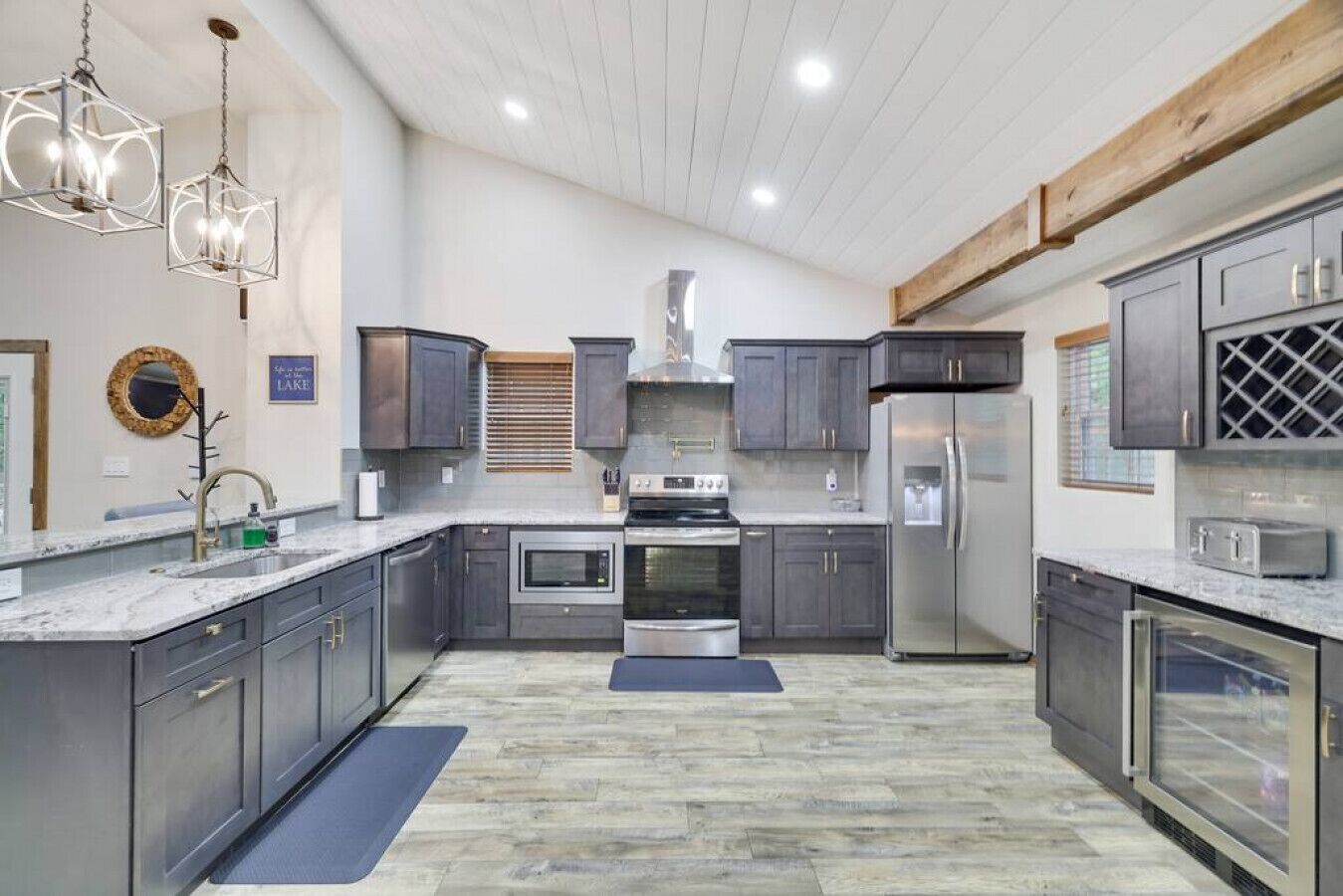 A modern kitchen with dark cabinets, stainless steel appliances, and a wooden ceiling.