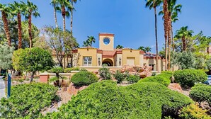 Un edificio con una torre circular, rodeado de palmeras y jardines bien cuidados.