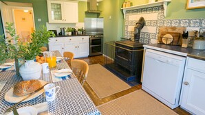 Una cocina con una mesa lista para el desayuno, estufa, horno, lavavajillas y una cafetera.