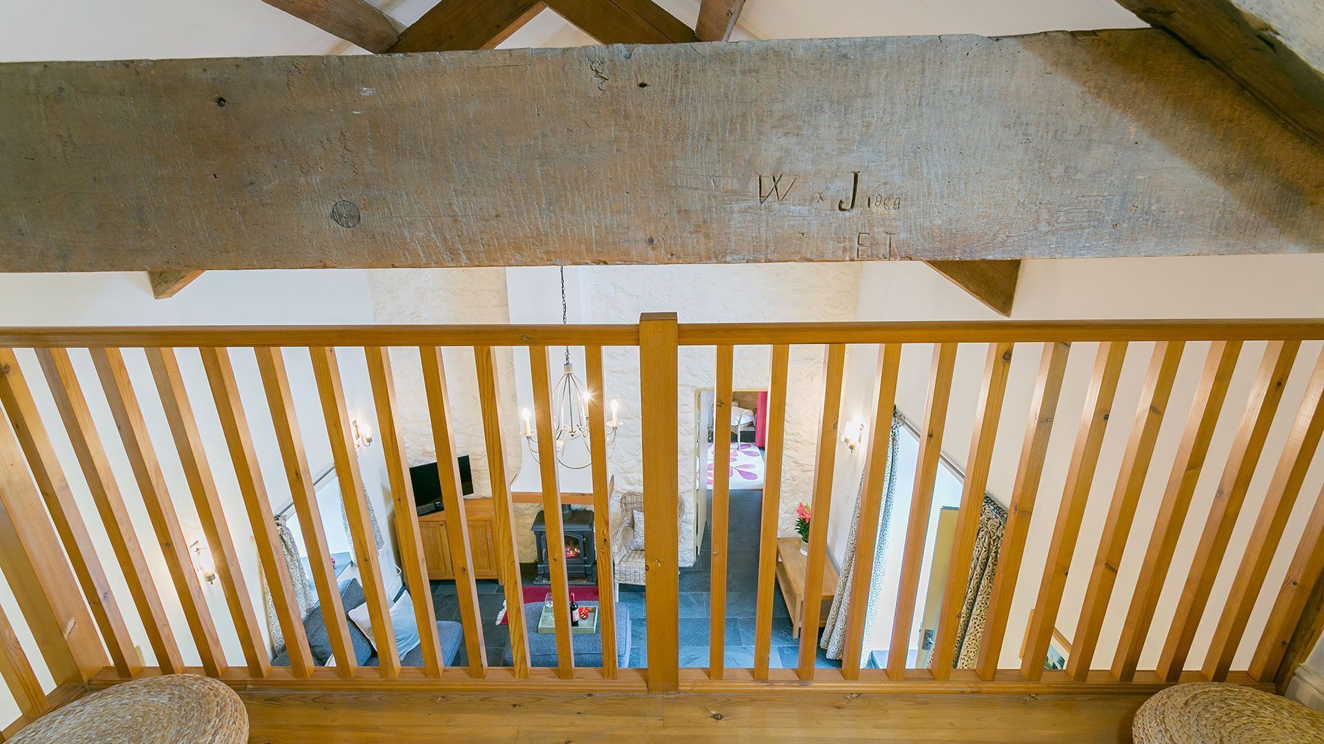 A wooden balcony railing with a view of a cozy interior space, including a fireplace and seating area.