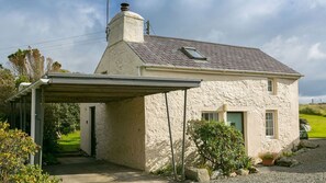 A single-story stone house with a sloped roof, a chimney, and a covered porch.