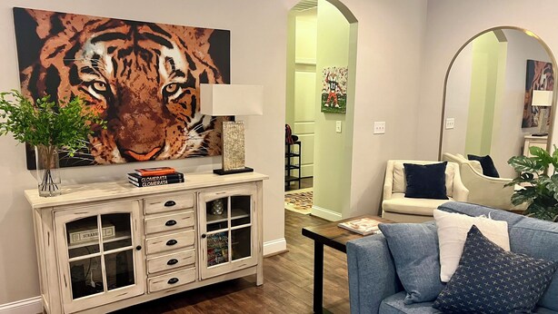 Un salon comprenant un canapé, un meuble, un tableau représentant un tigre et un miroir.