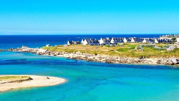 A coastal area with clear turquoise waters, a sandy beach, and white houses with conical roofs. - 3* Beach house in Plouescat in front of the sea (Plouescat)