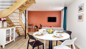 A dining area with a round table, chairs, and a wooden staircase. - 3* Beach house in Plouescat in front of the sea (Plouescat)