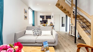 A modern living room with a grey sofa, a wooden coffee table, and a staircase. - 3* Beach house in Plouescat in front of the sea (Plouescat)