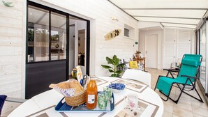 A dining area with a table set for two, featuring a basket, a bottle, and a tray with glasses. - 3* Beach house in Plouescat in front of the sea (Plouescat)