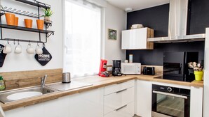 A modern kitchen with white cabinets, a wooden countertop, a stainless steel sink, a coffee maker, a microwave, and an oven. - 3* Beach house in Plouescat in front of the sea (Plouescat)