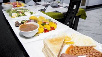 Una mesa de comedor con varios platos, entre ellos ensalada, patatas, frijoles y un sándwich.