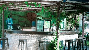 An outdoor bar area with a stone counter, stools, and a rustic wooden pergola. - Taj Residency Pokhara (Pokhara)