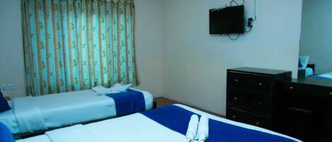 A hotel room with two beds, a flat-screen TV, a dresser, and a window with curtains.