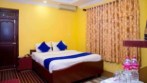 A hotel room with a bed, a table with a red checkered tablecloth, a water dispenser, and a bottle of water. - Taj Residency Pokhara (Pokhara)