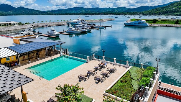 A marina with boats, a swimming pool, and a view of mountains. - Marina Flamingo (Cabo Velas)