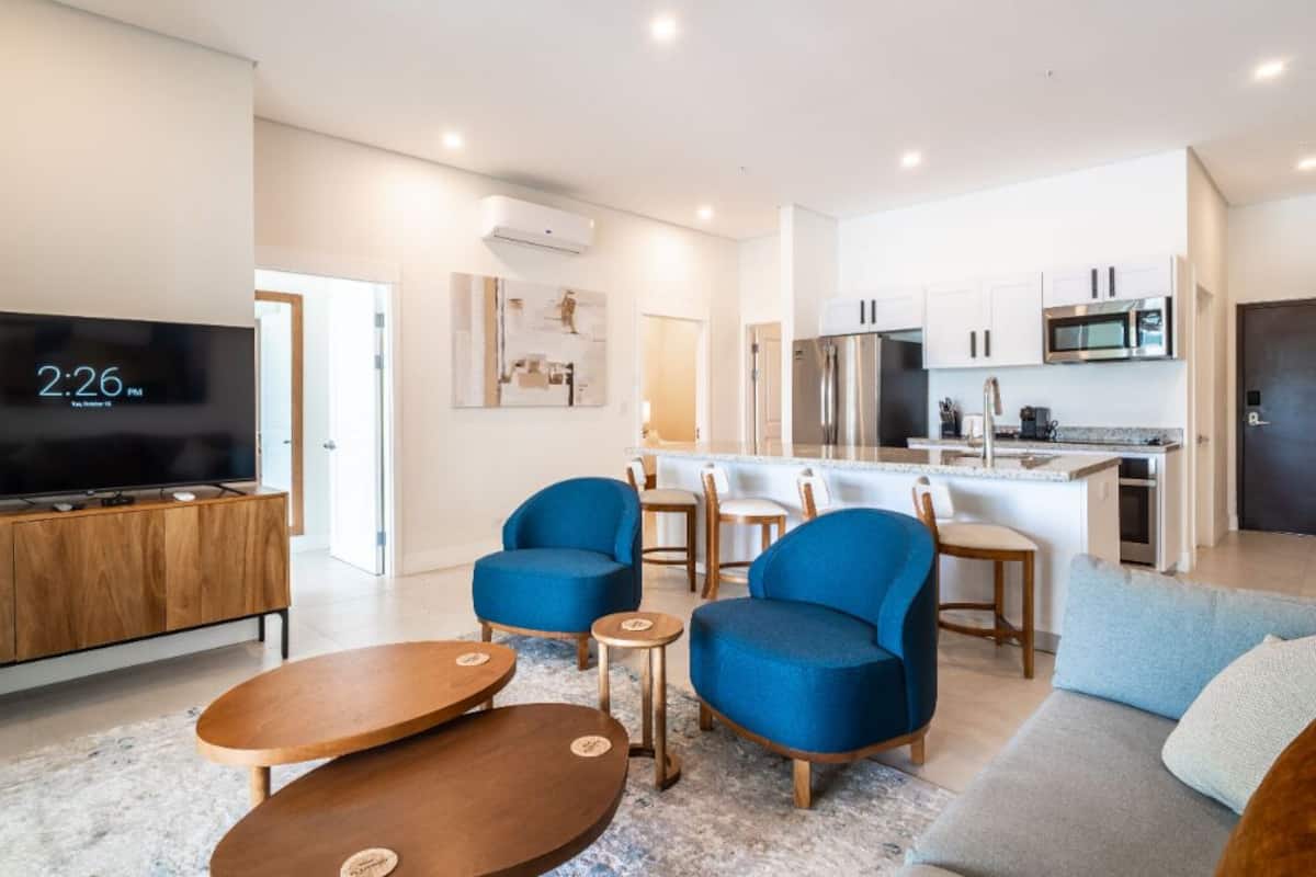 A modern living room with a TV, blue armchairs, and a sofa.