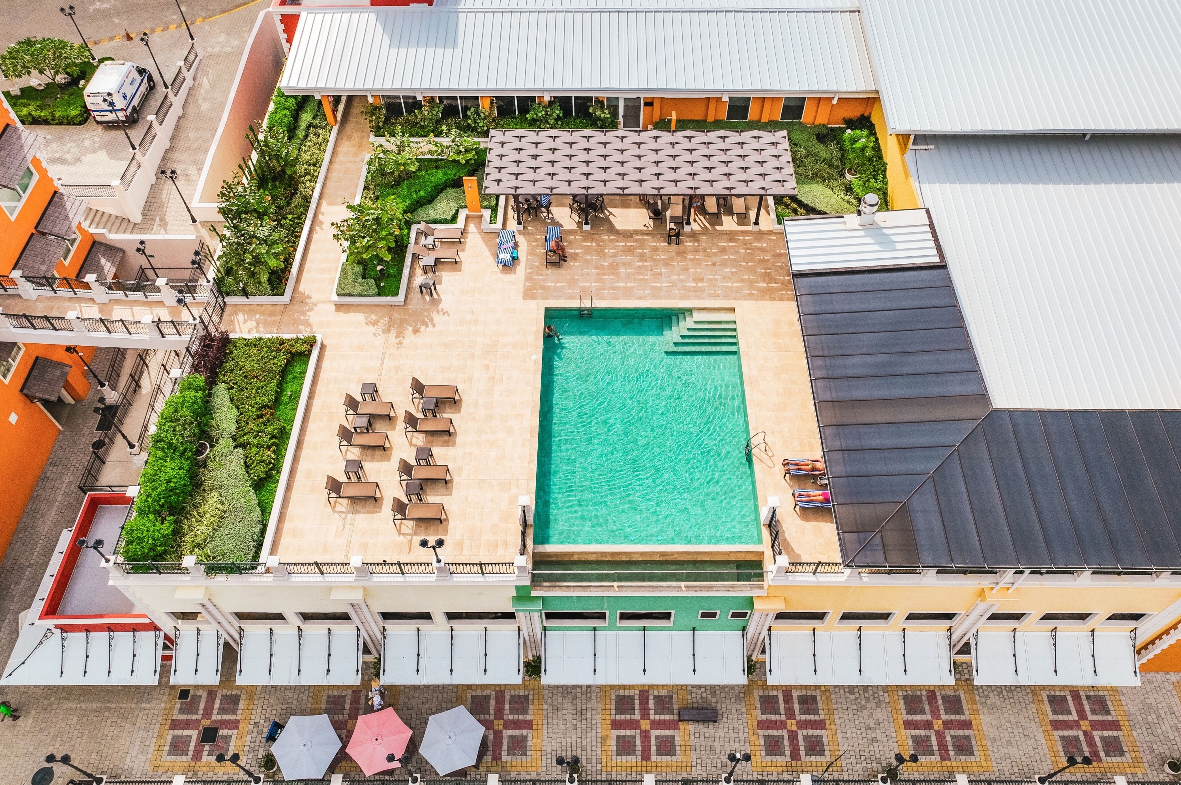 Vue aérienne d’un hôtel doté d’une piscine, d’un espace salon extérieur et d’une terrasse couverte.