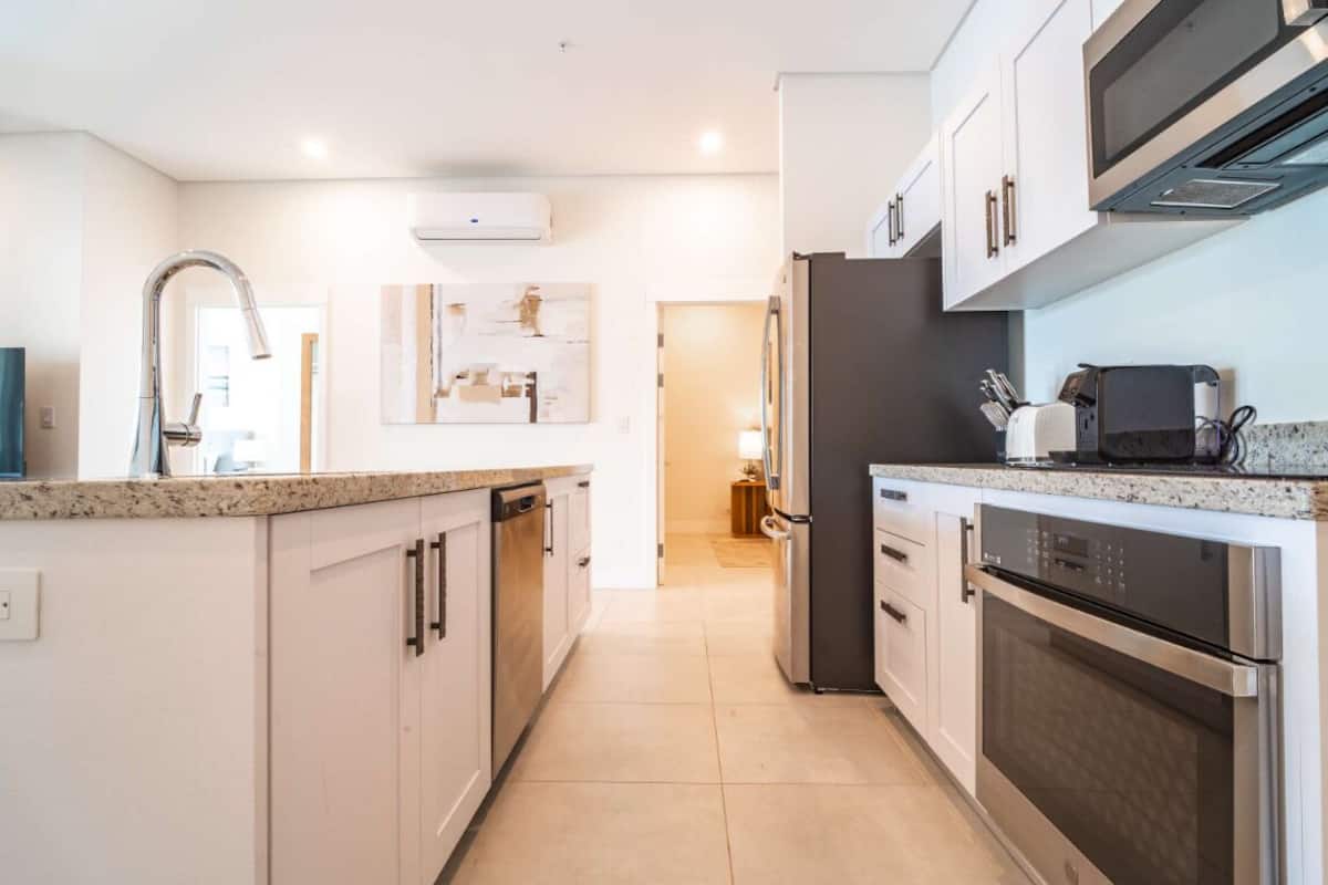 A modern kitchen with stainless steel appliances, white cabinetry, and a granite countertop.