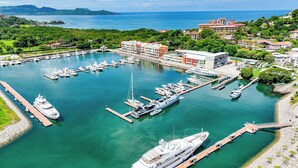A marina with multiple yachts docked, a large cruise ship, and a building with a red roof. - Marina Flamingo (Cabo Velas)