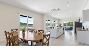 A spacious kitchen with a central island, large windows offering a view of the outdoors, and a dining area with a view of the sea. - Marina Flamingo (Cabo Velas)