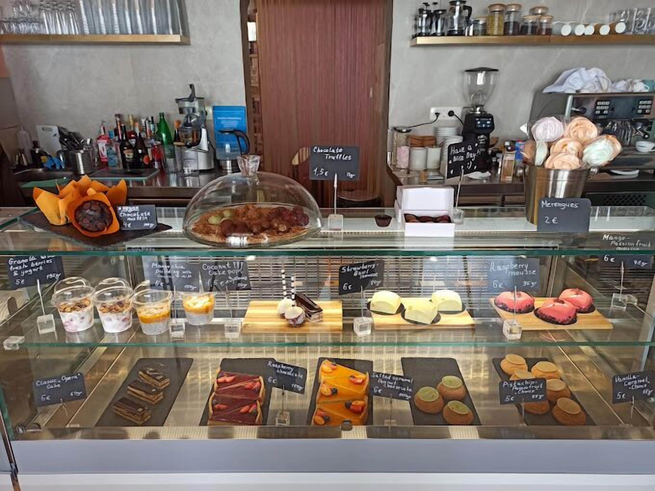 A bakery display case with various pastries and desserts, including chocolate muffins and raspberry tarts.