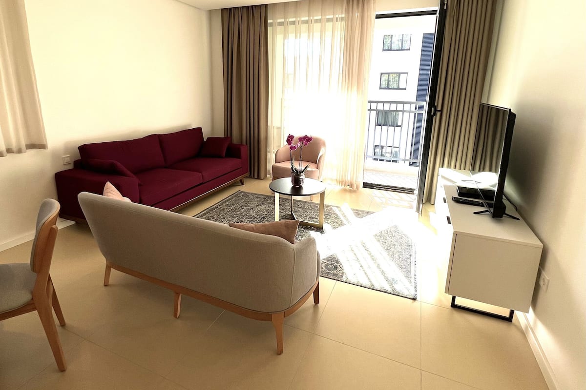 A living room with a sofa, chairs, a small table, and a TV.