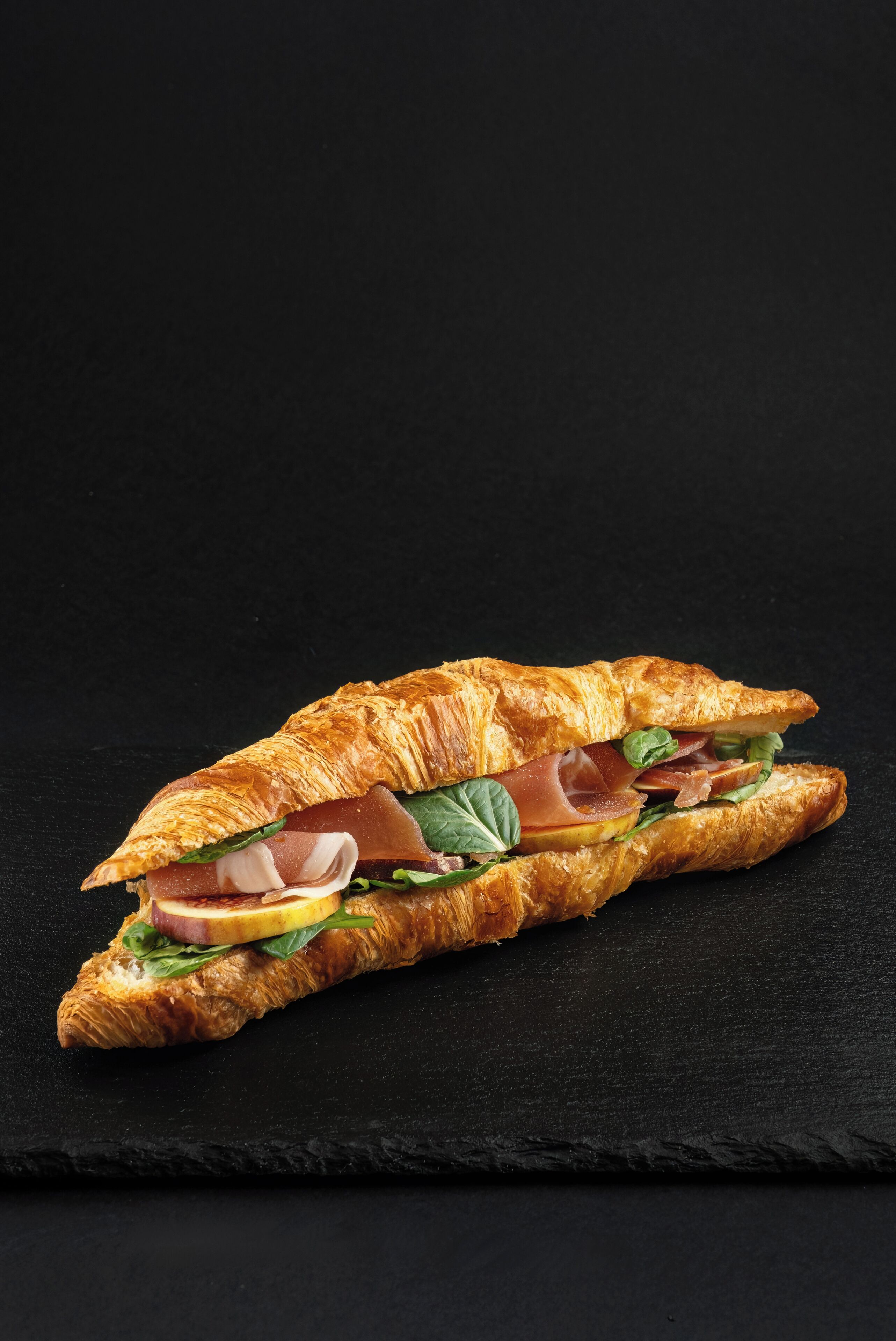 A sandwich on a black slate surface.