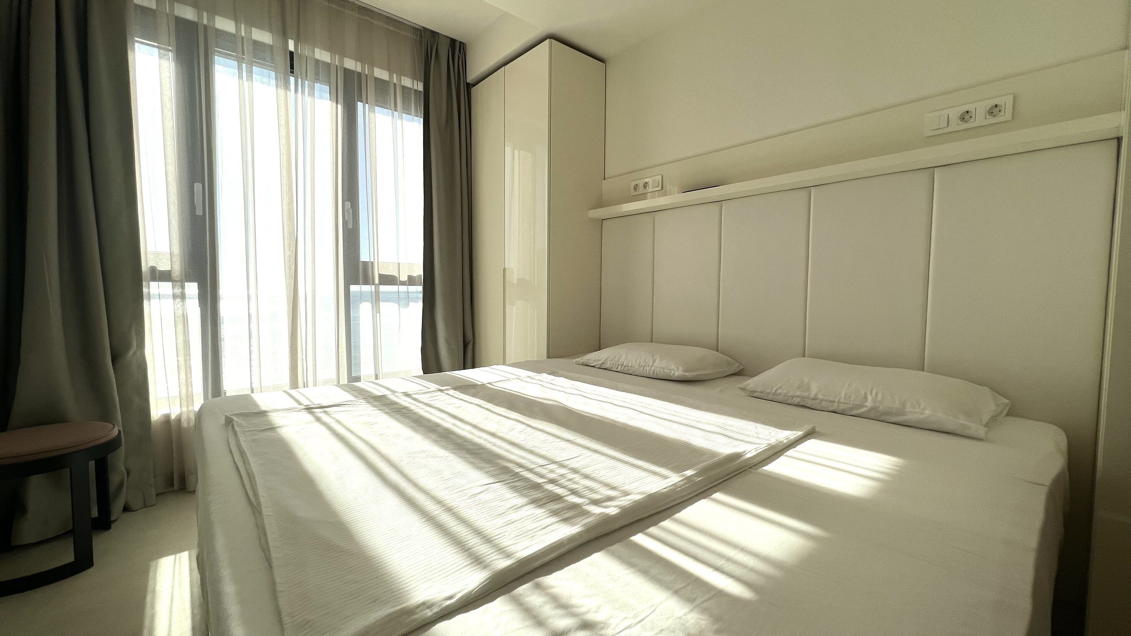 Een hotelkamer met een groot bed, een nachtkastje en een raam met gordijnen.