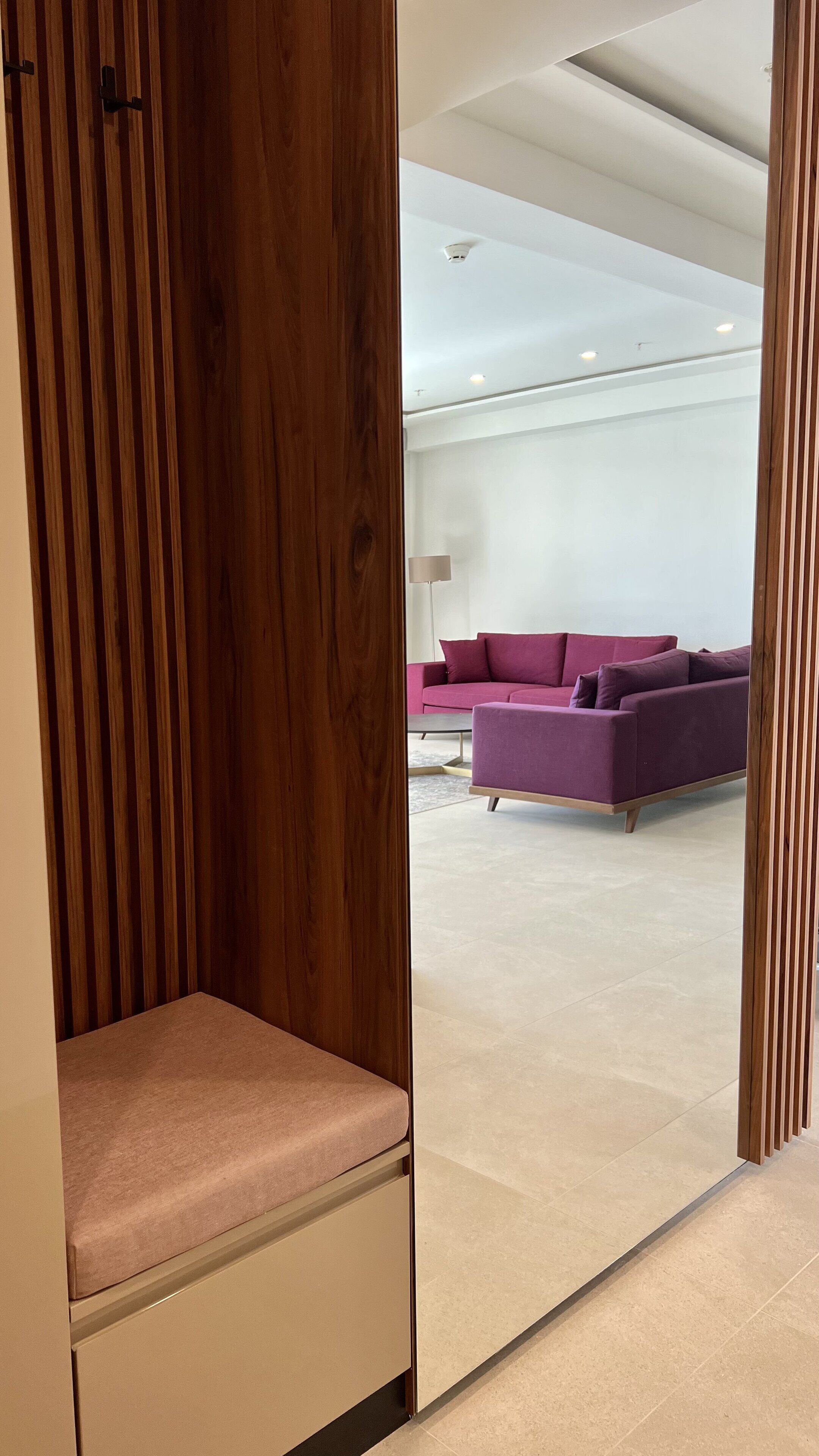 A modern room with a wooden partition, a pink sofa, and a white floor.
