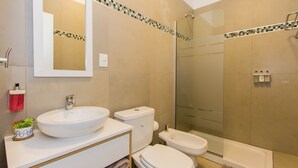 Ein Badezimmer mit Waschbecken, Toilette, Bidet und einer Duschkabine aus Glas.