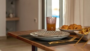 A dining table with plates, a glass, and a bowl of pastries. - MAGNOLIA Luxury Chania Central Apartments (Chania)