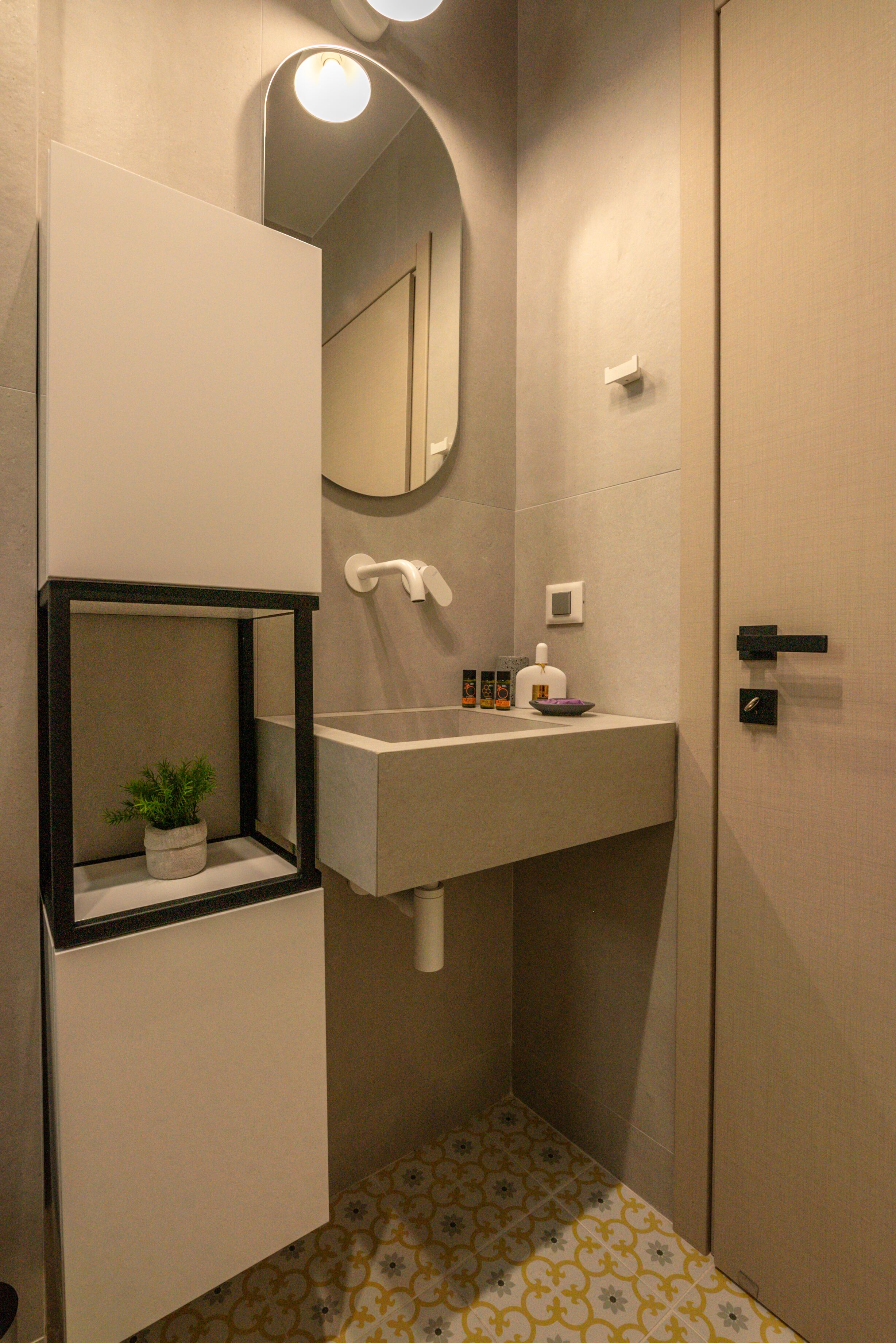 A bathroom with a white sink, a mirror, a small potted plant, and a toilet.