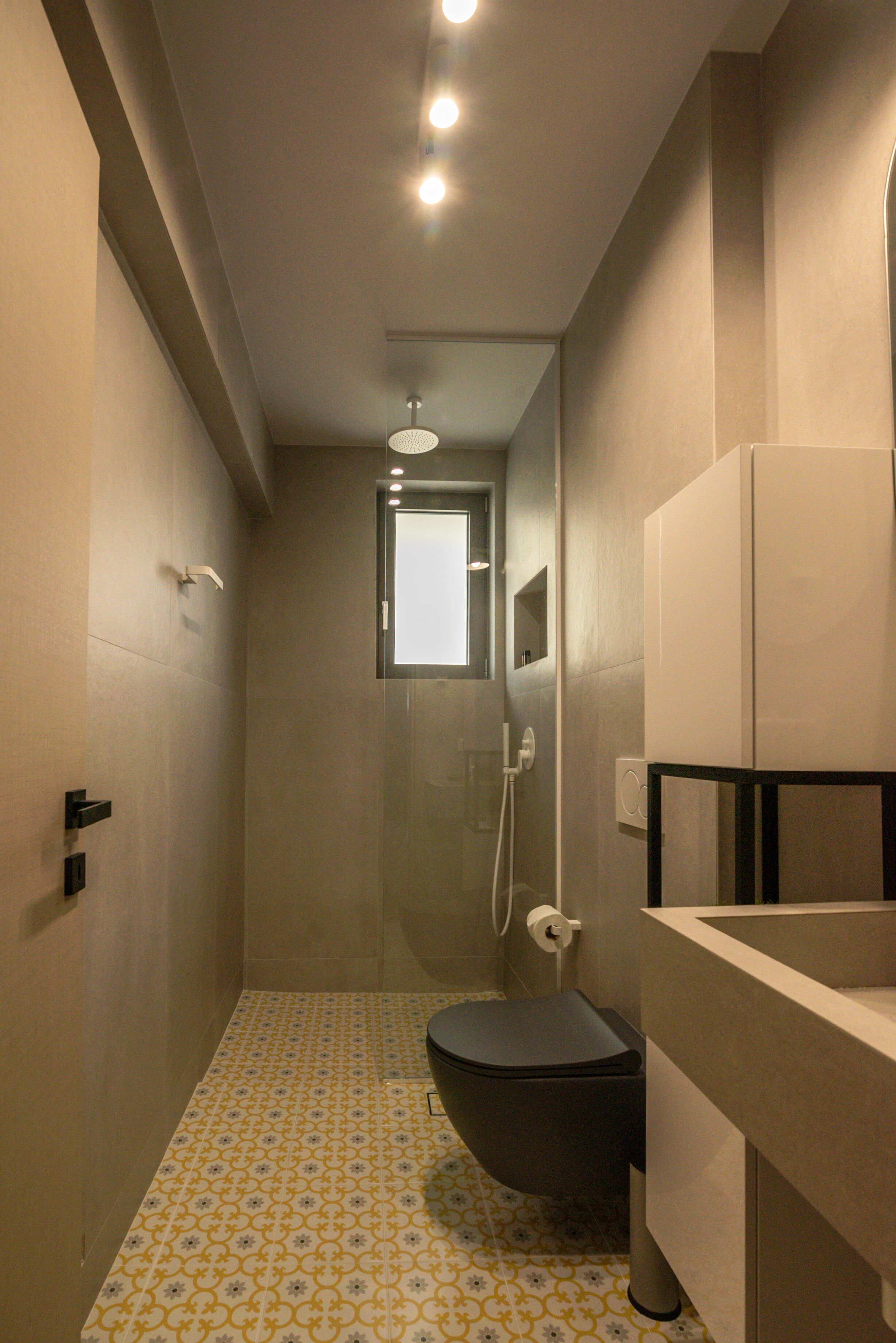 Un baño estrecho con inodoro, ducha y lavamanos.